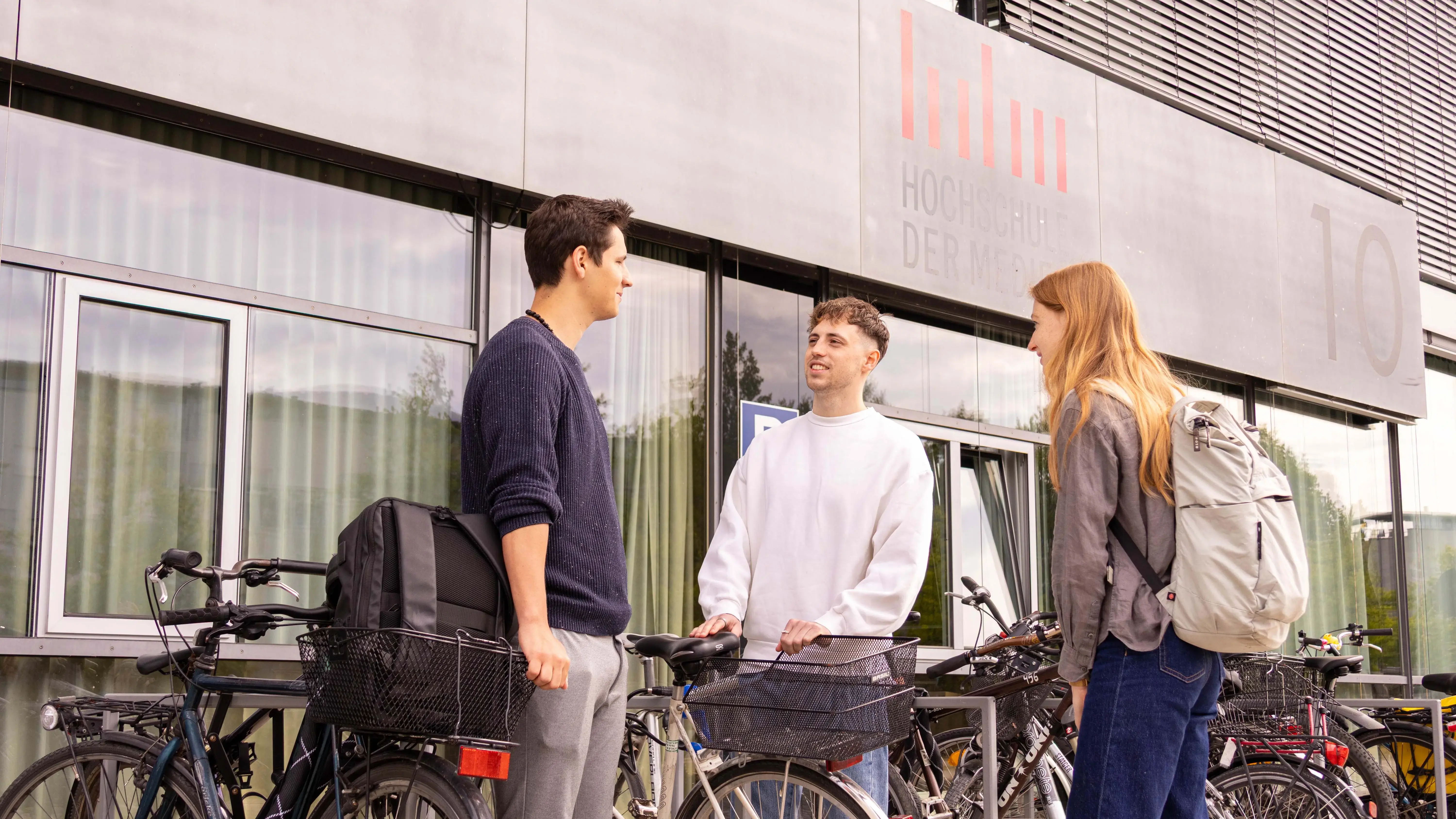Studierende unterhalten sich bei den Fahrradständern.