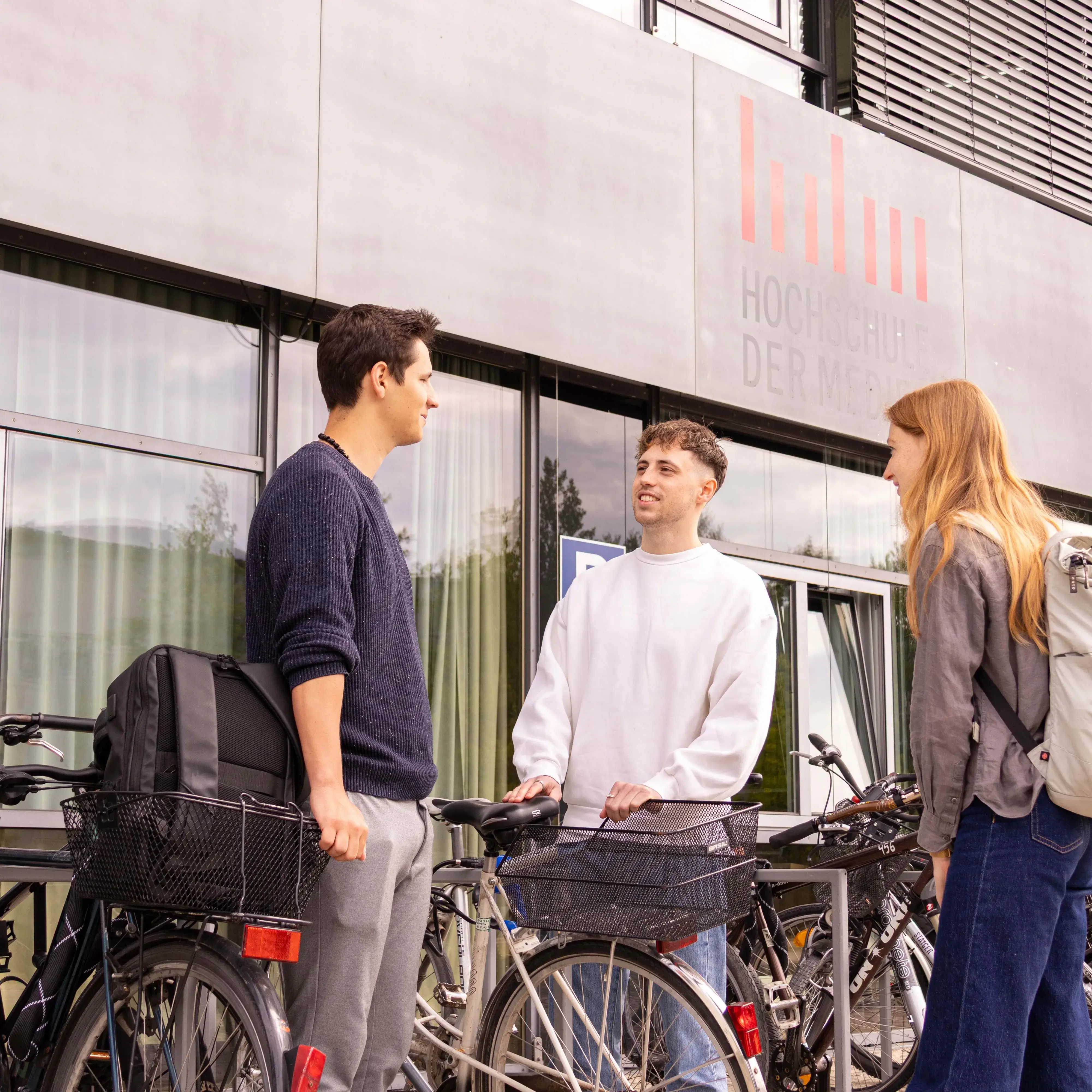 Studierende unterhalten sich bei den Fahrradständern.