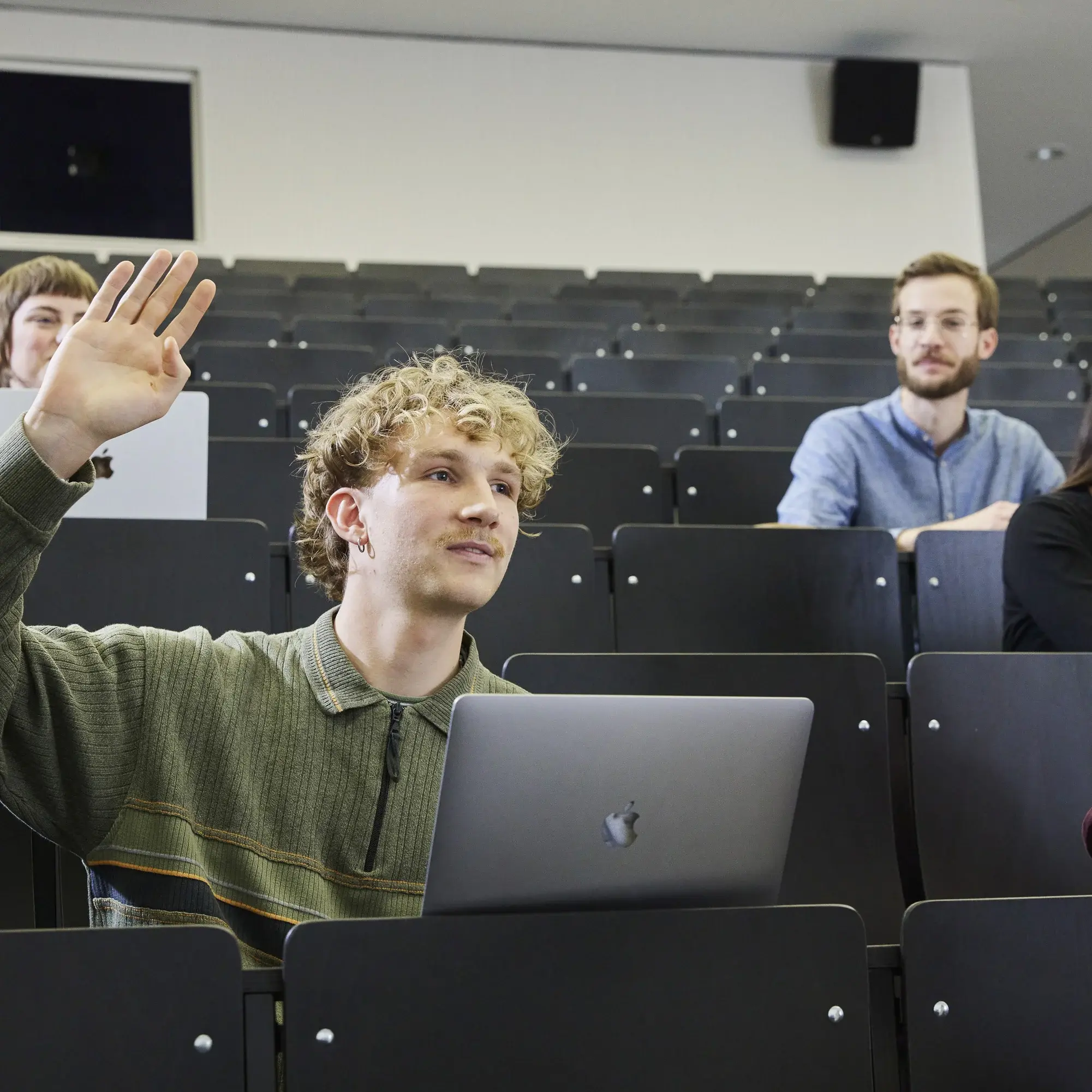 Ein Studierender hebt die Hand in einer Vorlesung.
