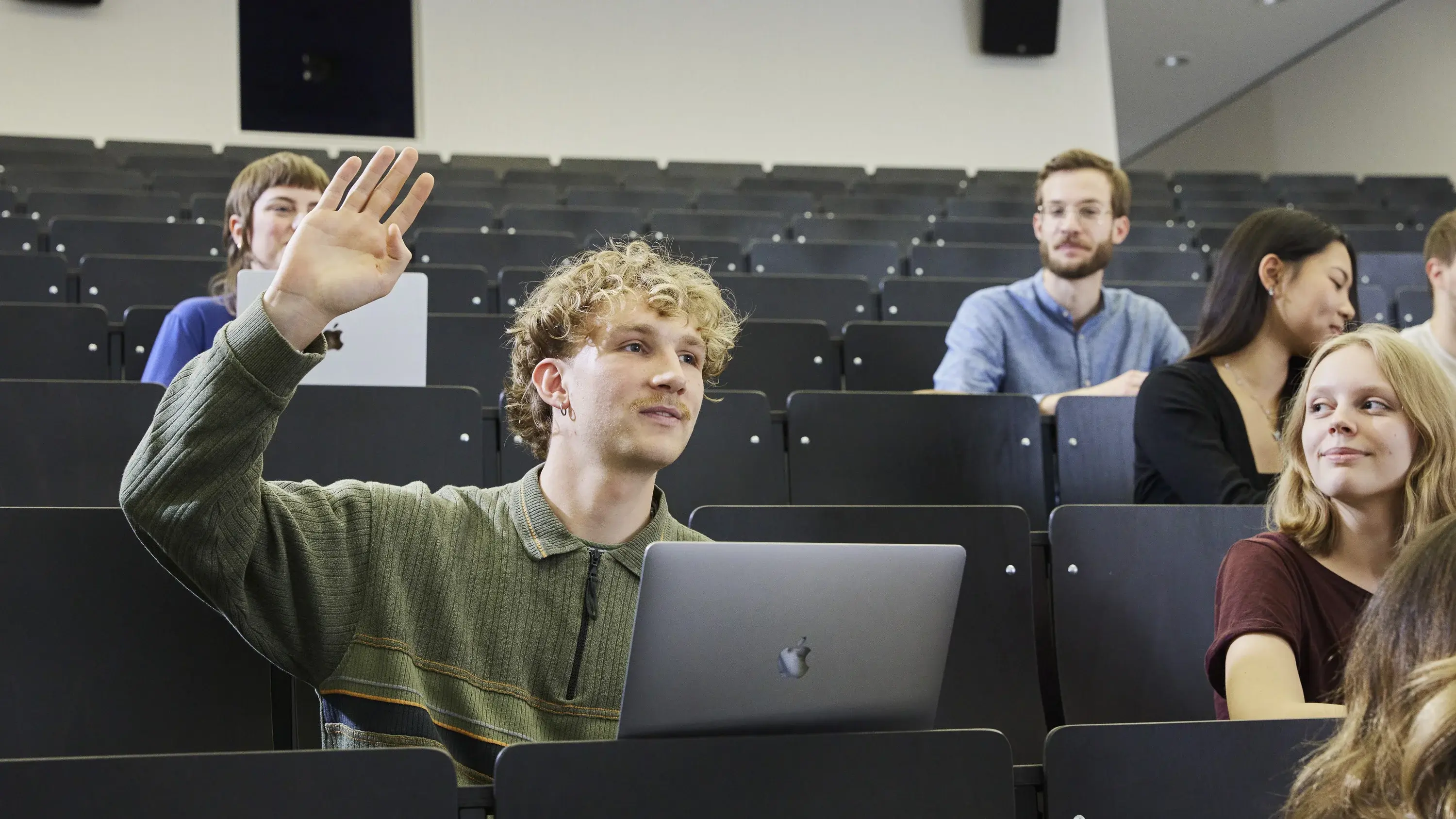 Ein Studierender hebt die Hand in einer Vorlesung.