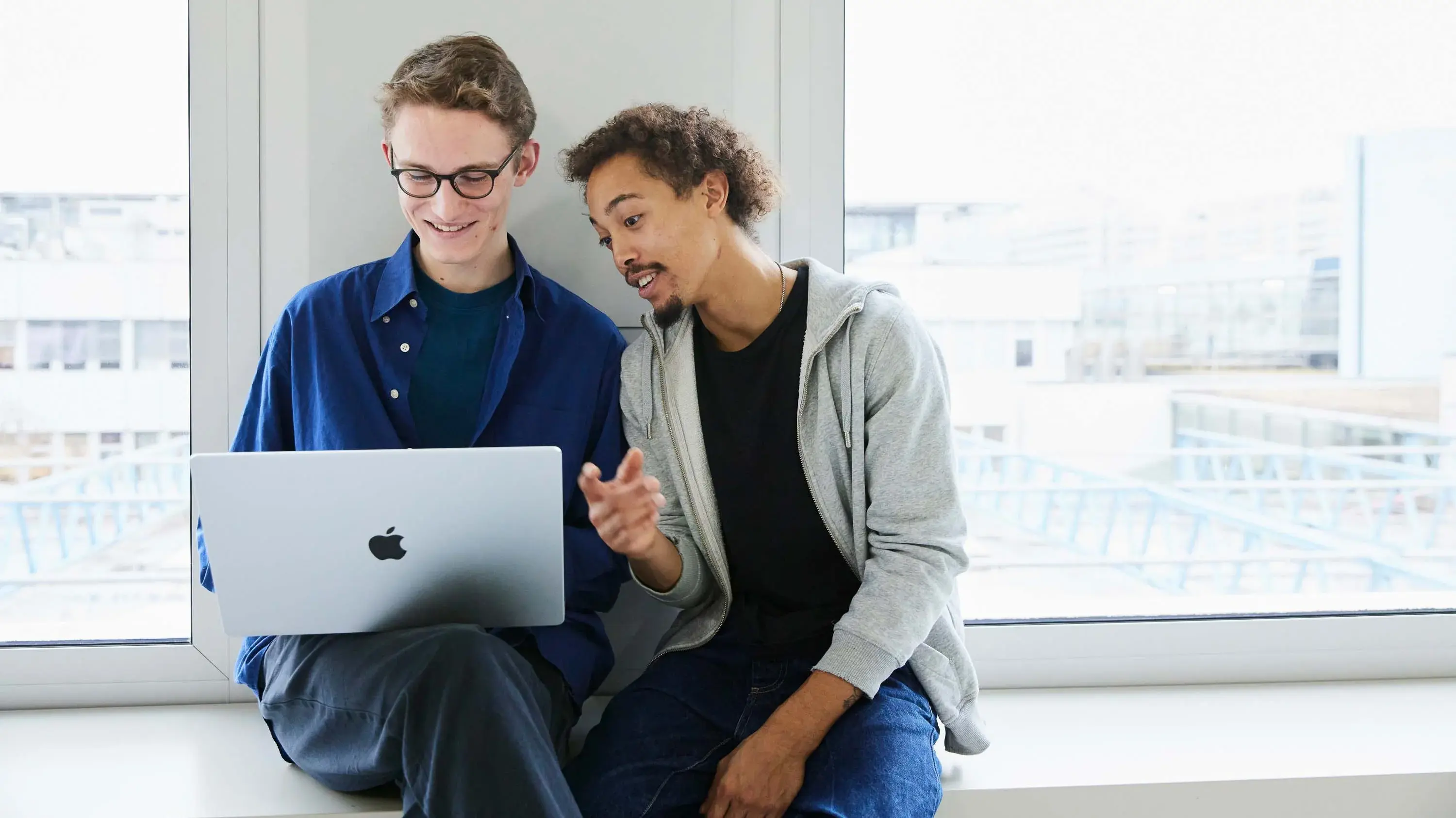 Zwei Studierende arbeiten an einem Laptop.