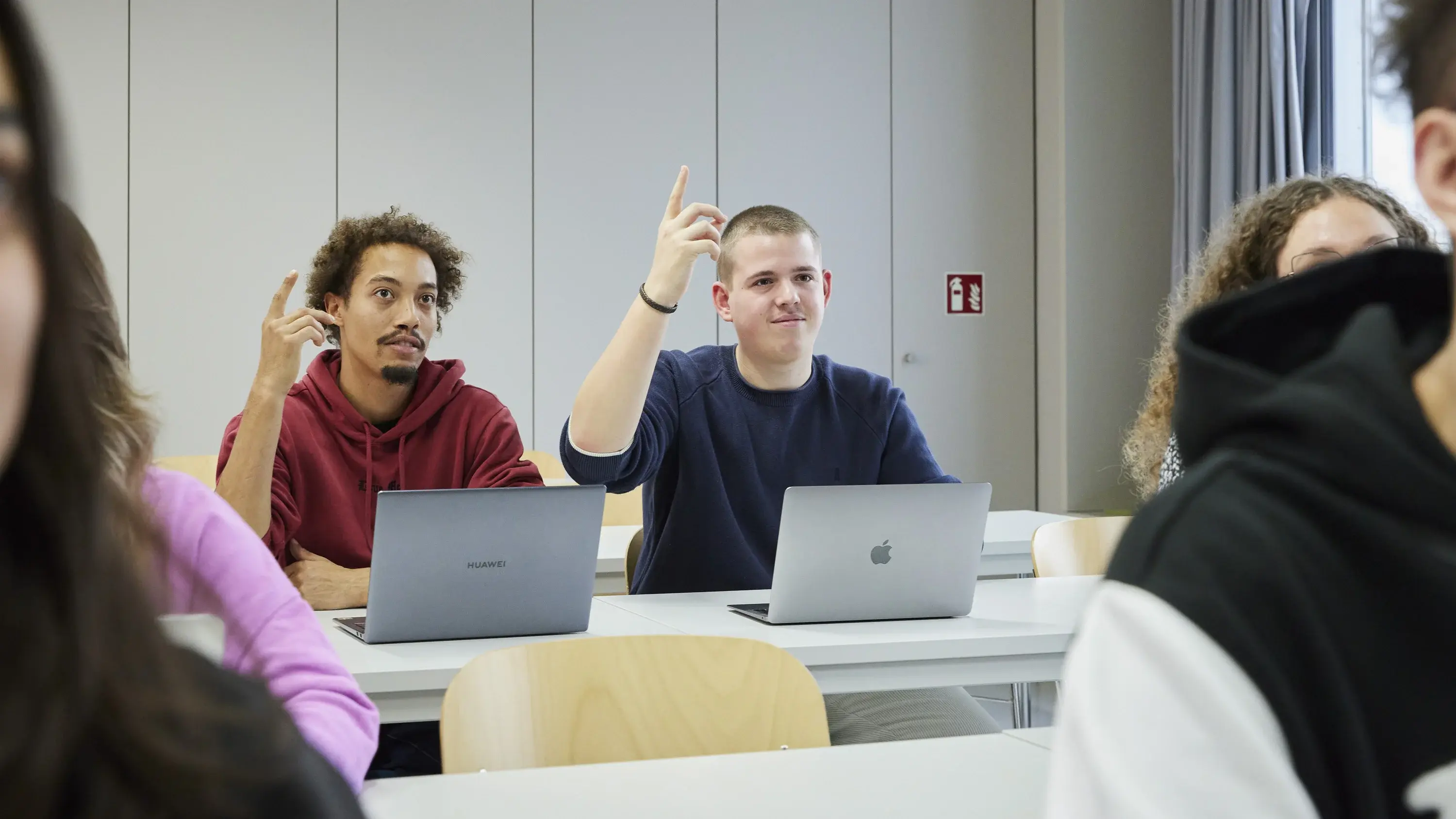 Zwei Studierende melden sich in der Vorlesung.