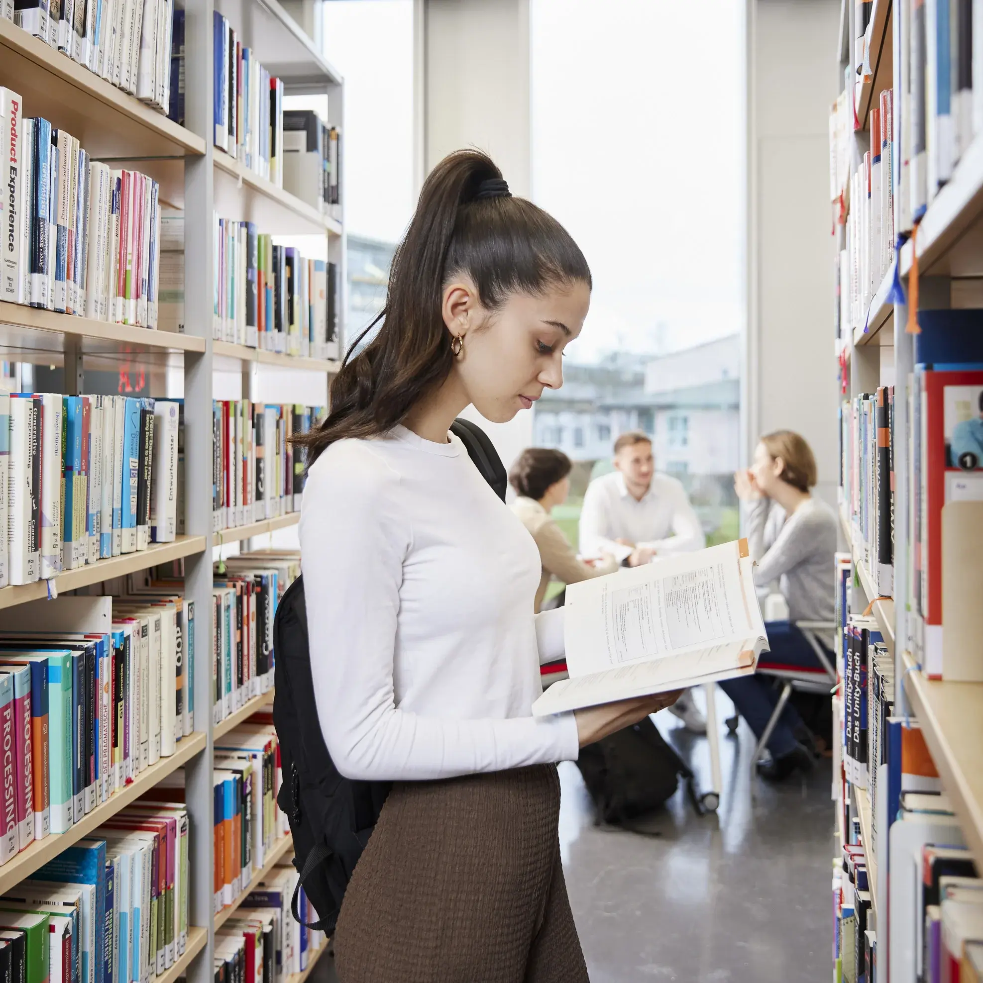 Eine Studierende liest ein Buch in der Bibliothek der Hochschule der Medien.