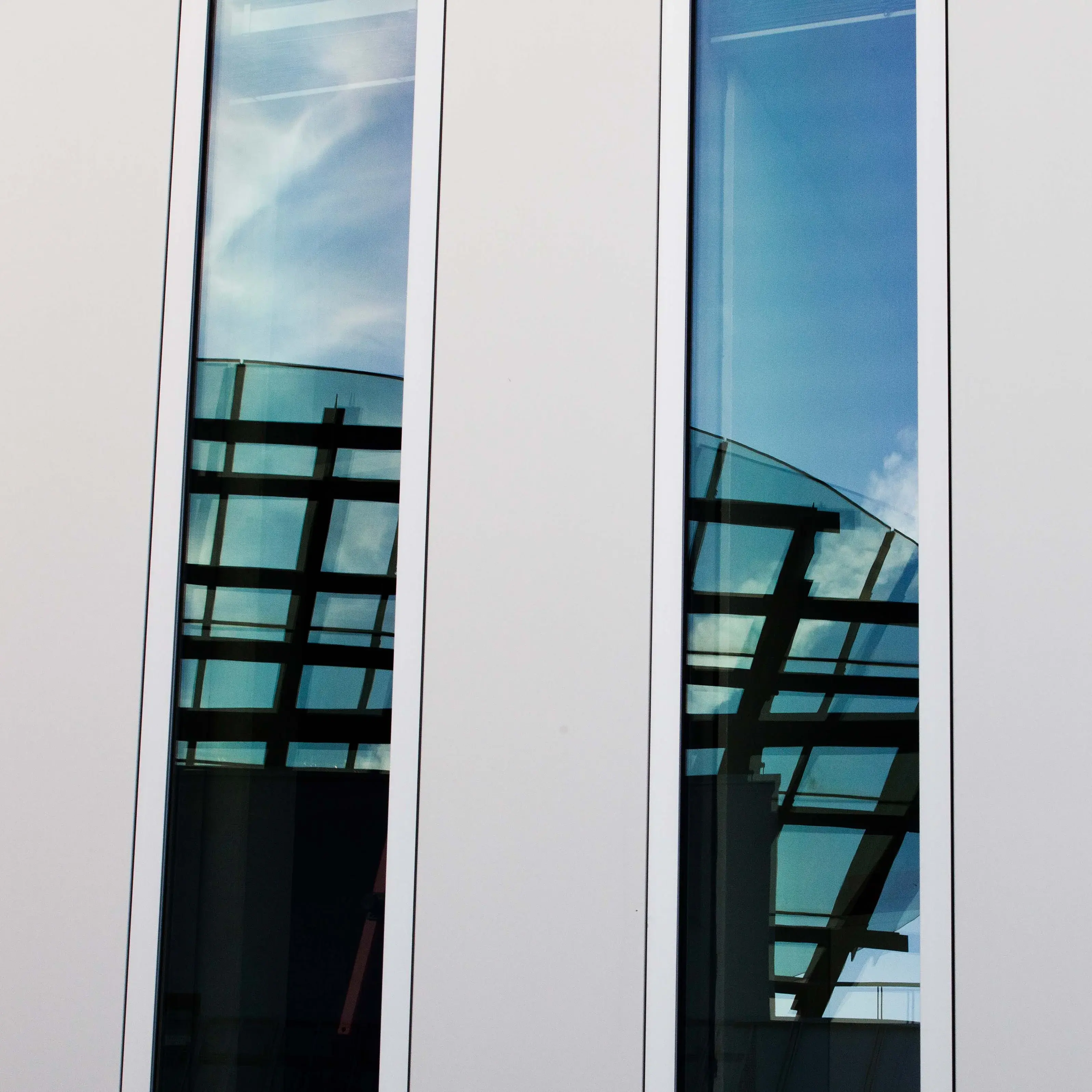 Close-up of a university building, with the main building reflected in its windows.