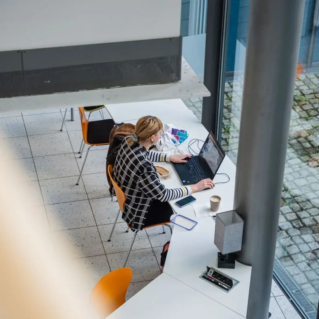 Studentin arbeitet mit Laptop in Foyer