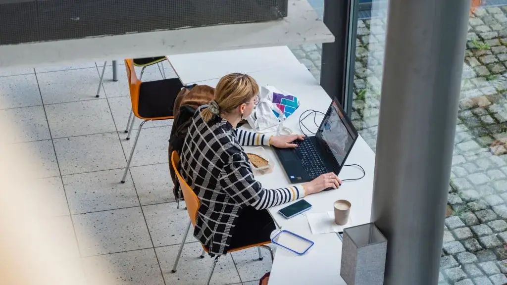 Studentin arbeitet mit Laptop in Foyer