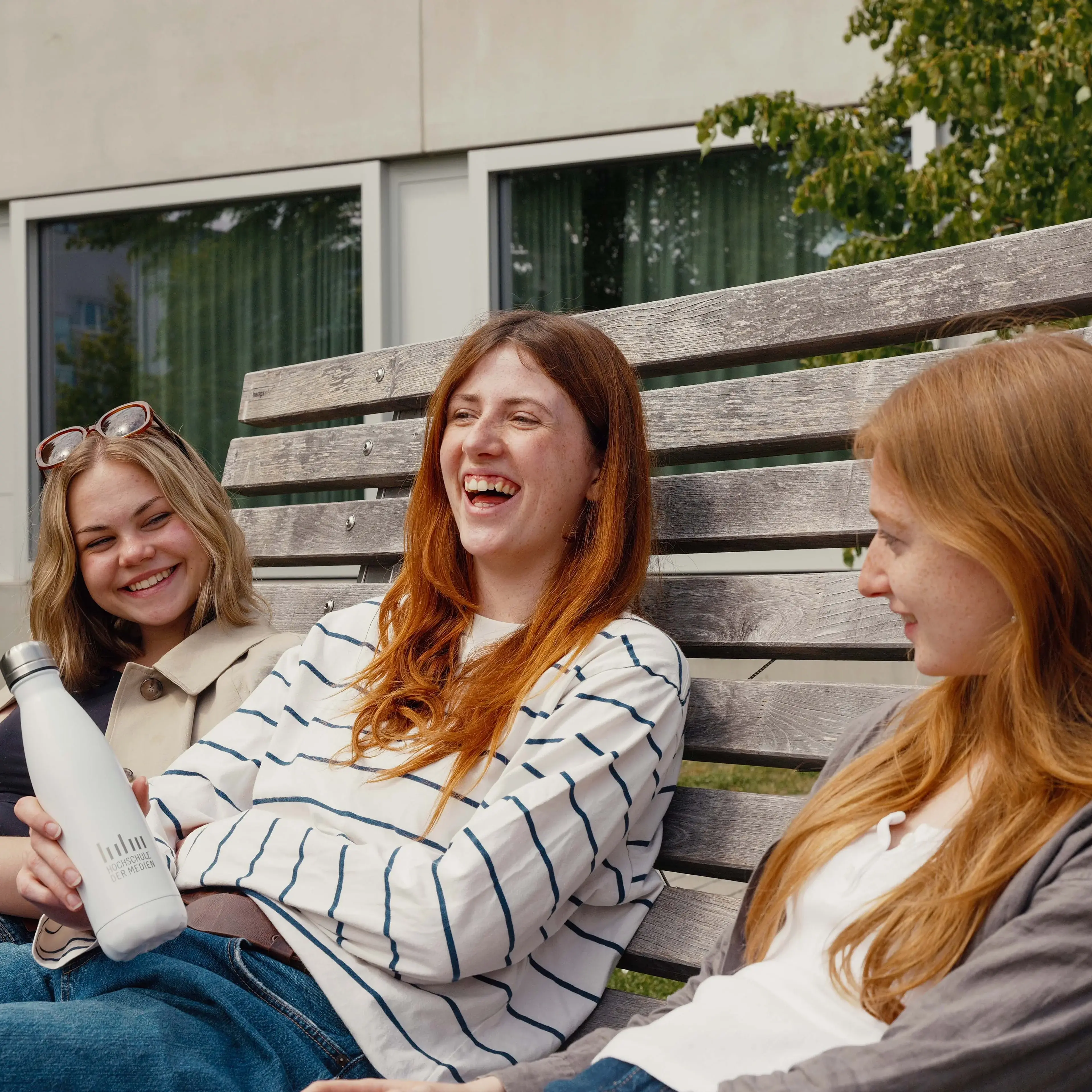 Studierende verbringen ihre Pause auf dem sonnigen Campus der Hochschule der Medien