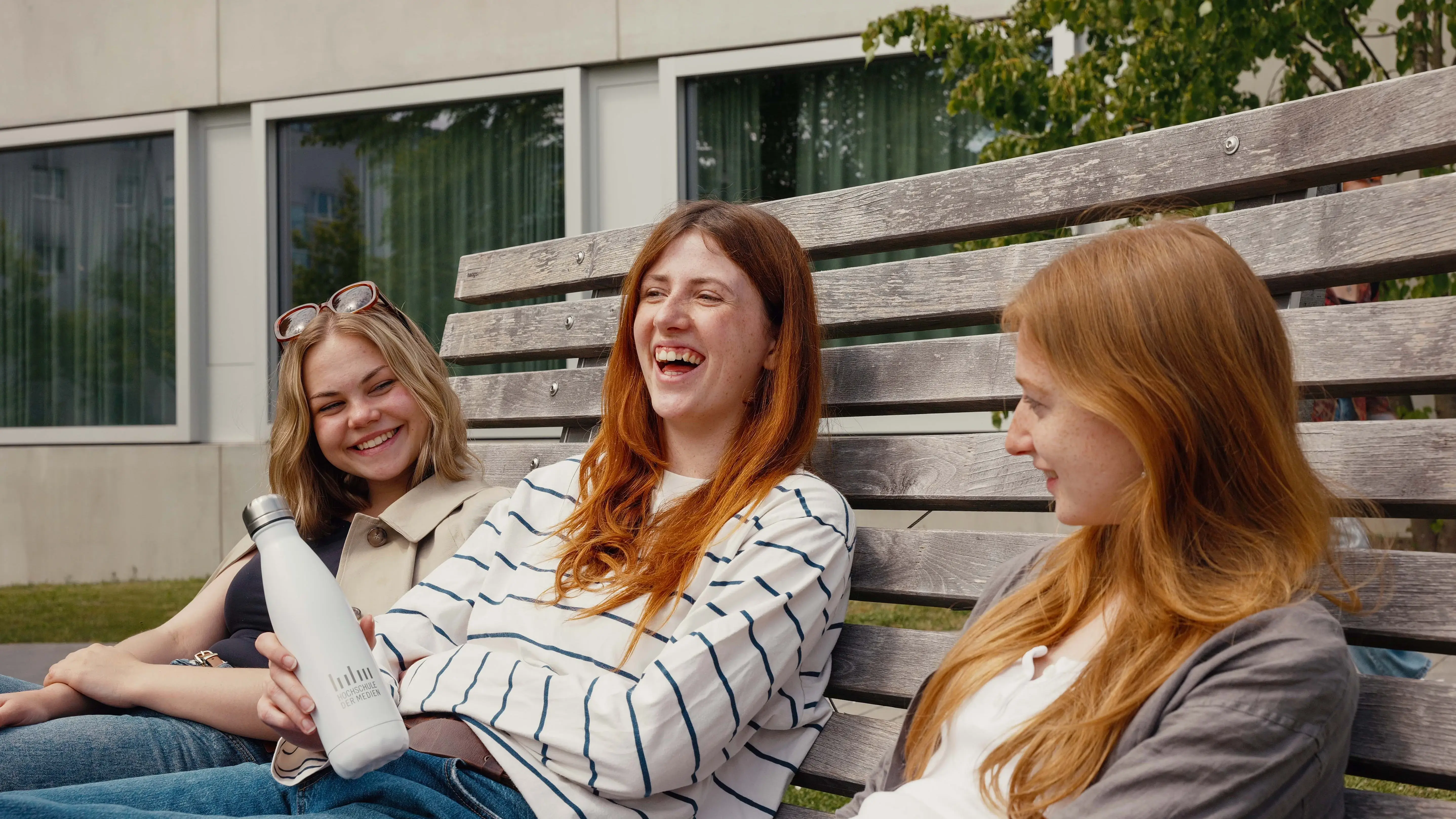 Studierende verbringen ihre Pause auf dem sonnigen Campus der Hochschule der Medien