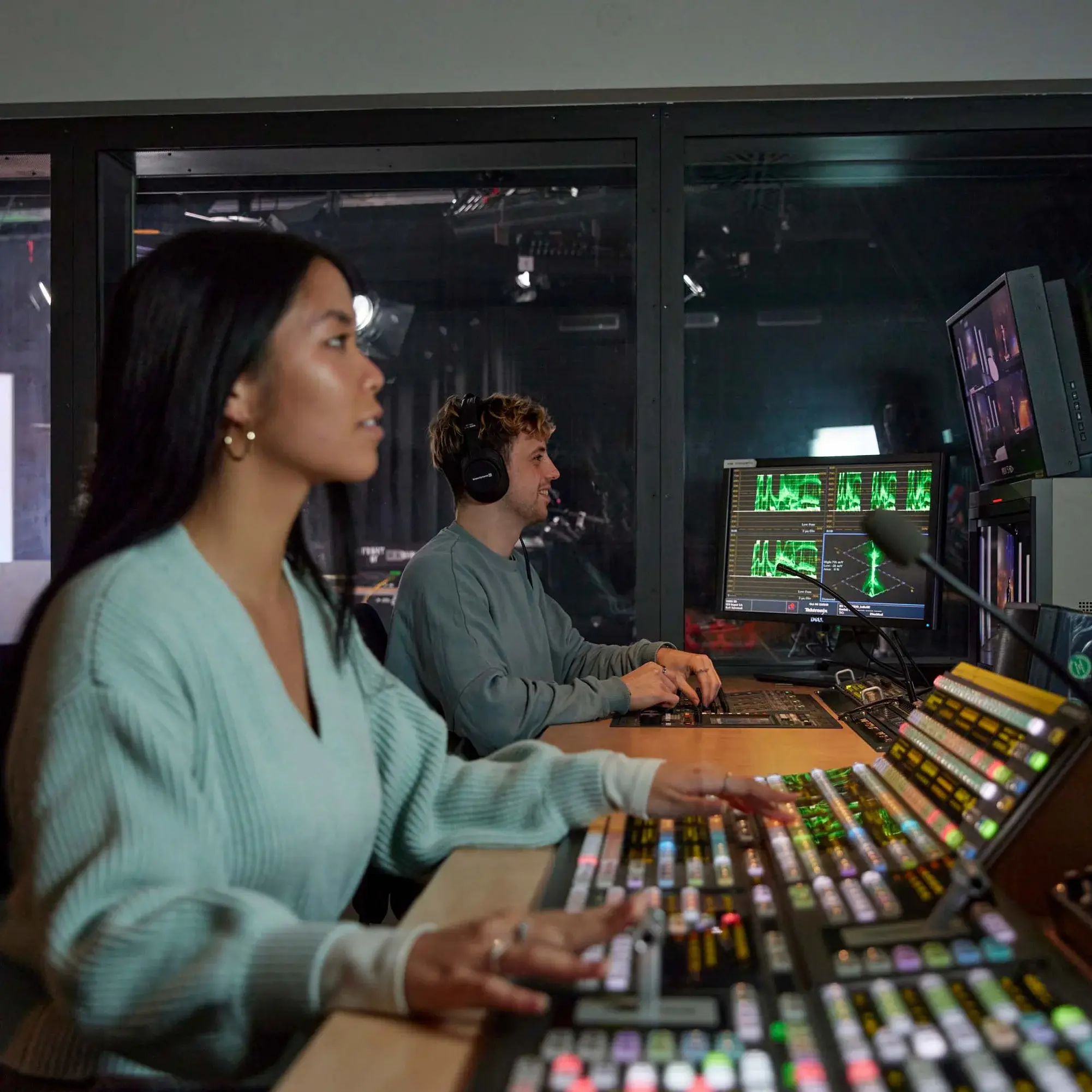 Im Technikraum des Fernsehstudios überwacht und betreut eine Studentin die Aufnahme einer Sendung.