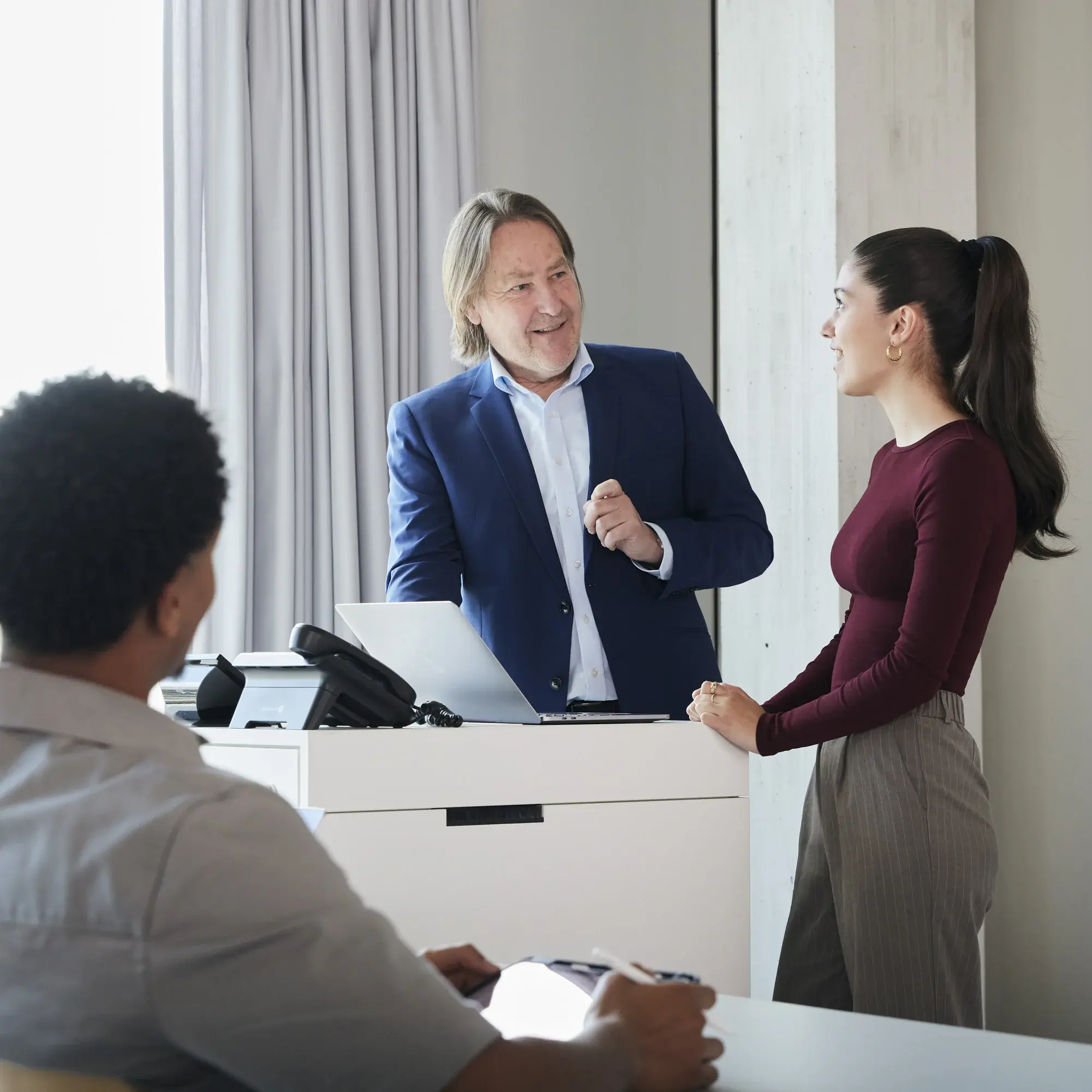 Ein Professor unterhält sich in einer Vorlesung mit einer Studentin am Pult.
