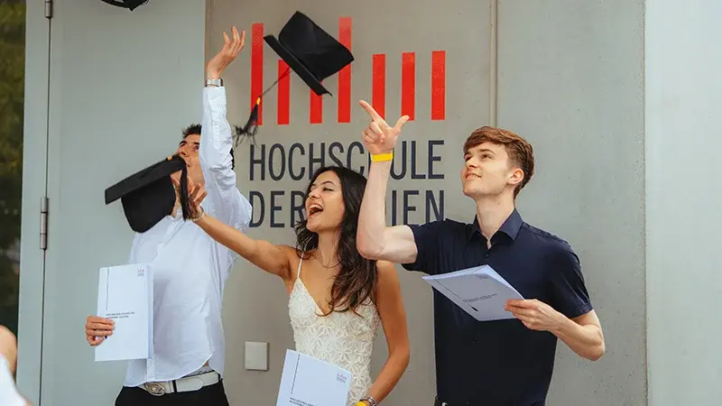 Absolventen feiern vor dem Hochschulgebäude