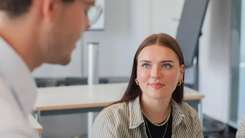Eine Studentin im Gespräch mit einem Dozenten