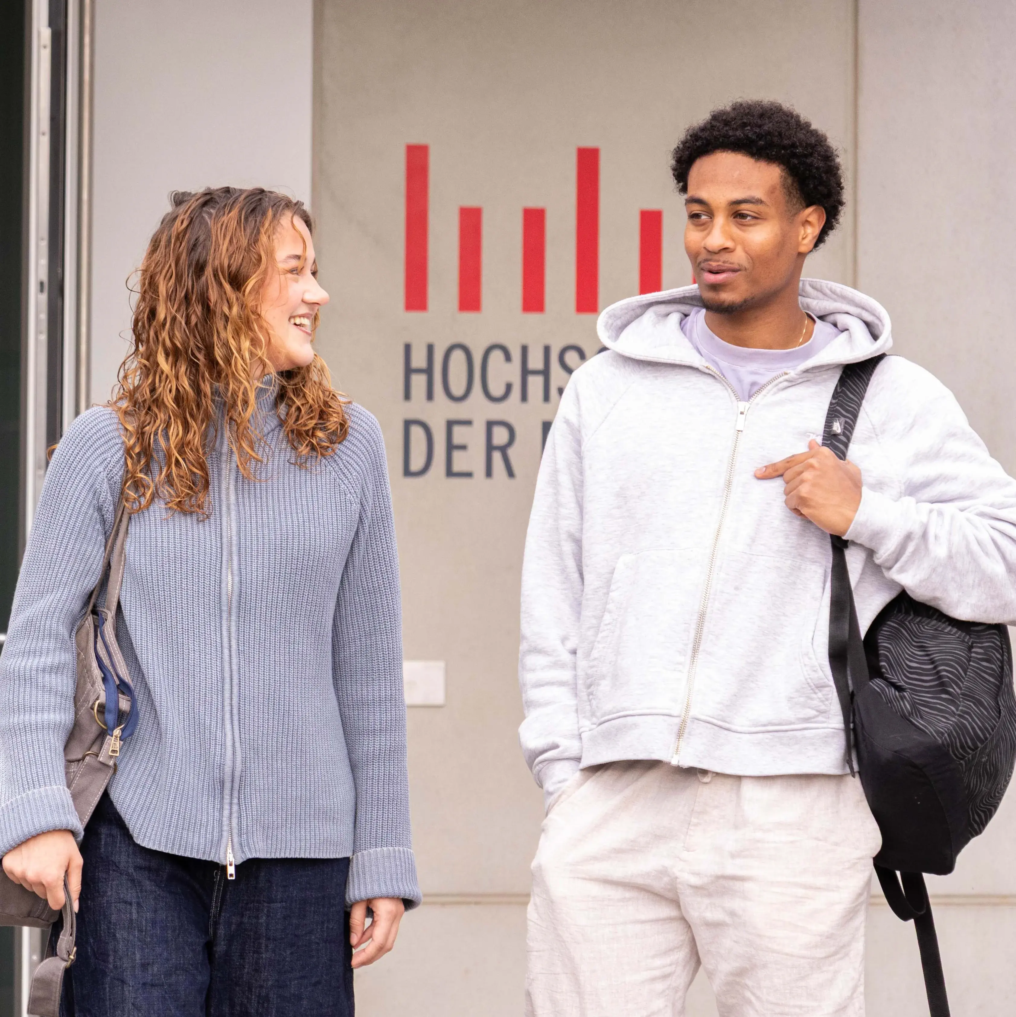 Studierende unterhalten sich beim Verlassen der Hochschule der Medien.