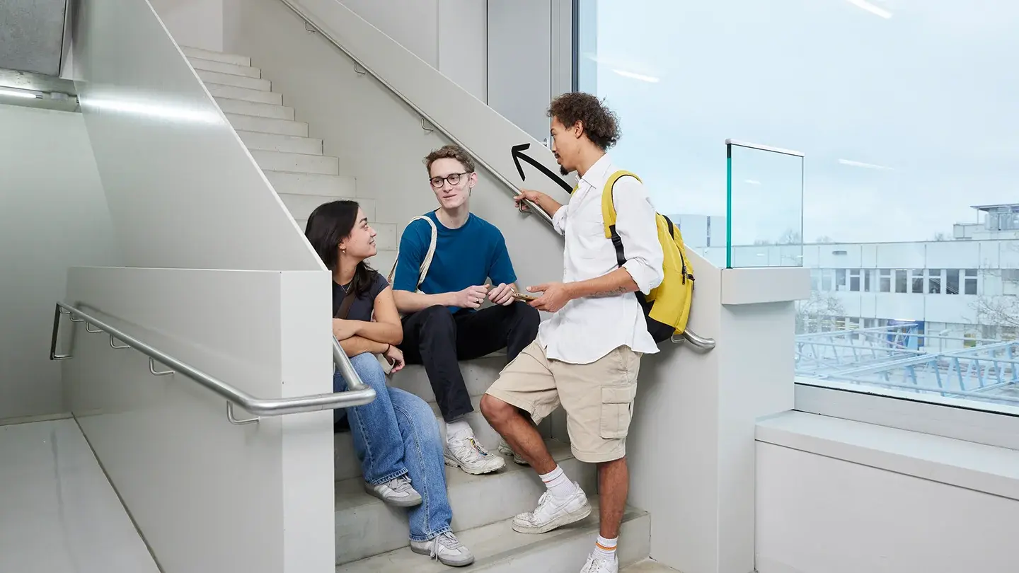 Studierende unterhalten sich im Treppenhaus.