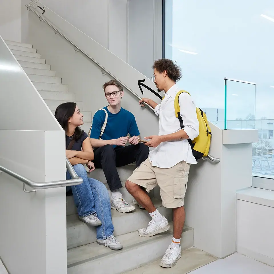 Studierende unterhalten sich im Treppenhaus.
