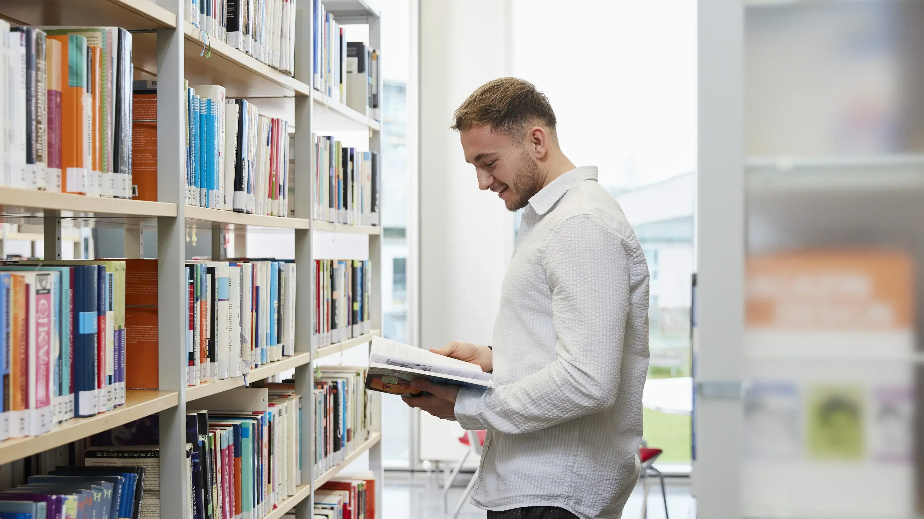 Ein Studierender liest ein Buch in der Bibliothek der Hochschule der Medien.