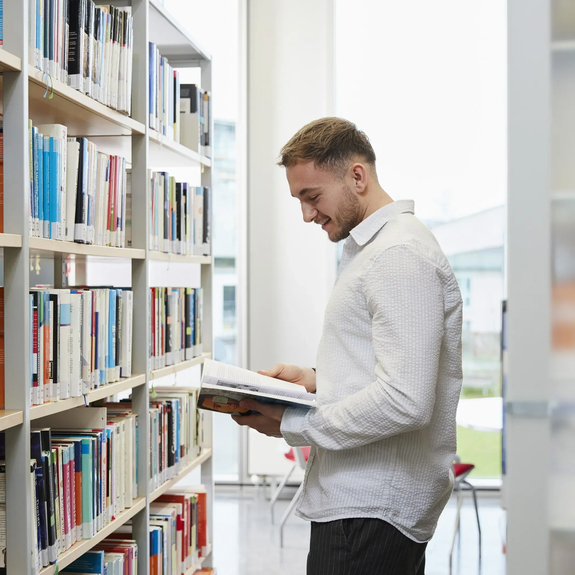 Ein Studierender liest ein Buch in der Bibliothek der Hochschule der Medien.