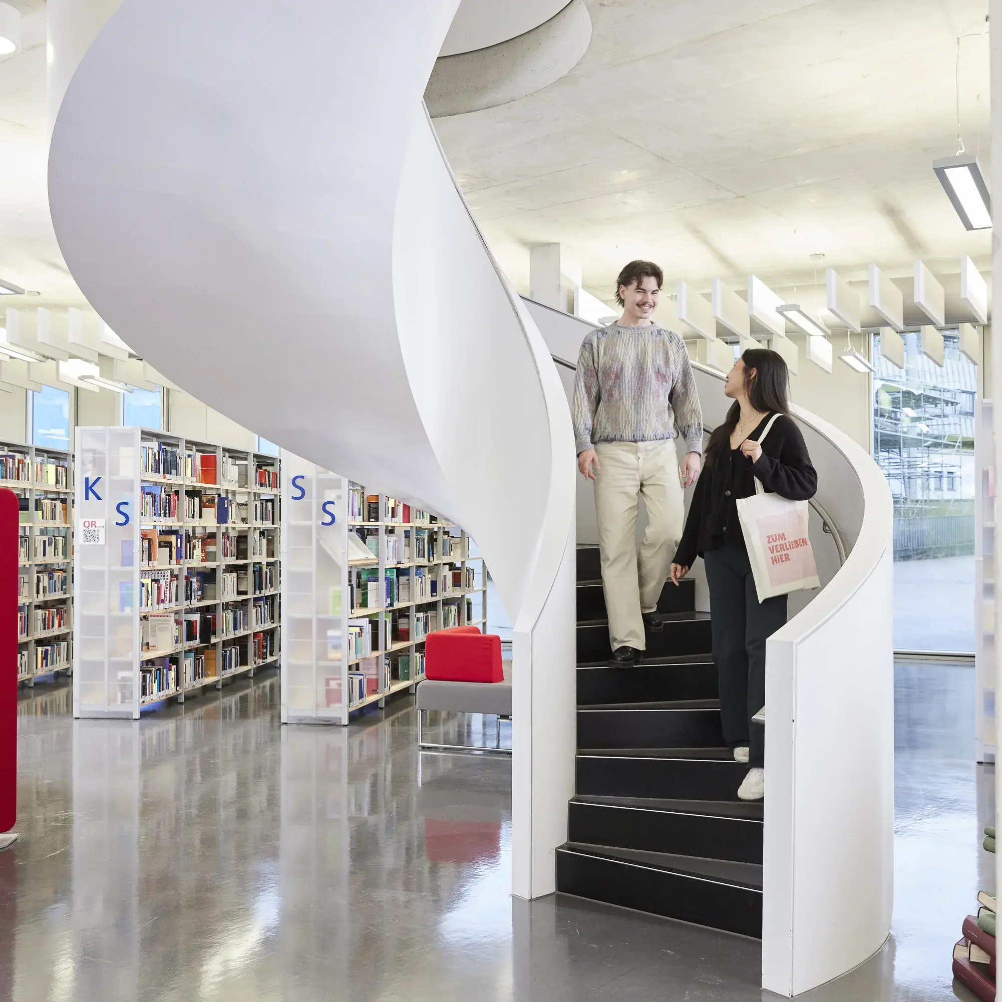 Studierende auf der Treppe in der Bibliothek der Hochschule der Medien.