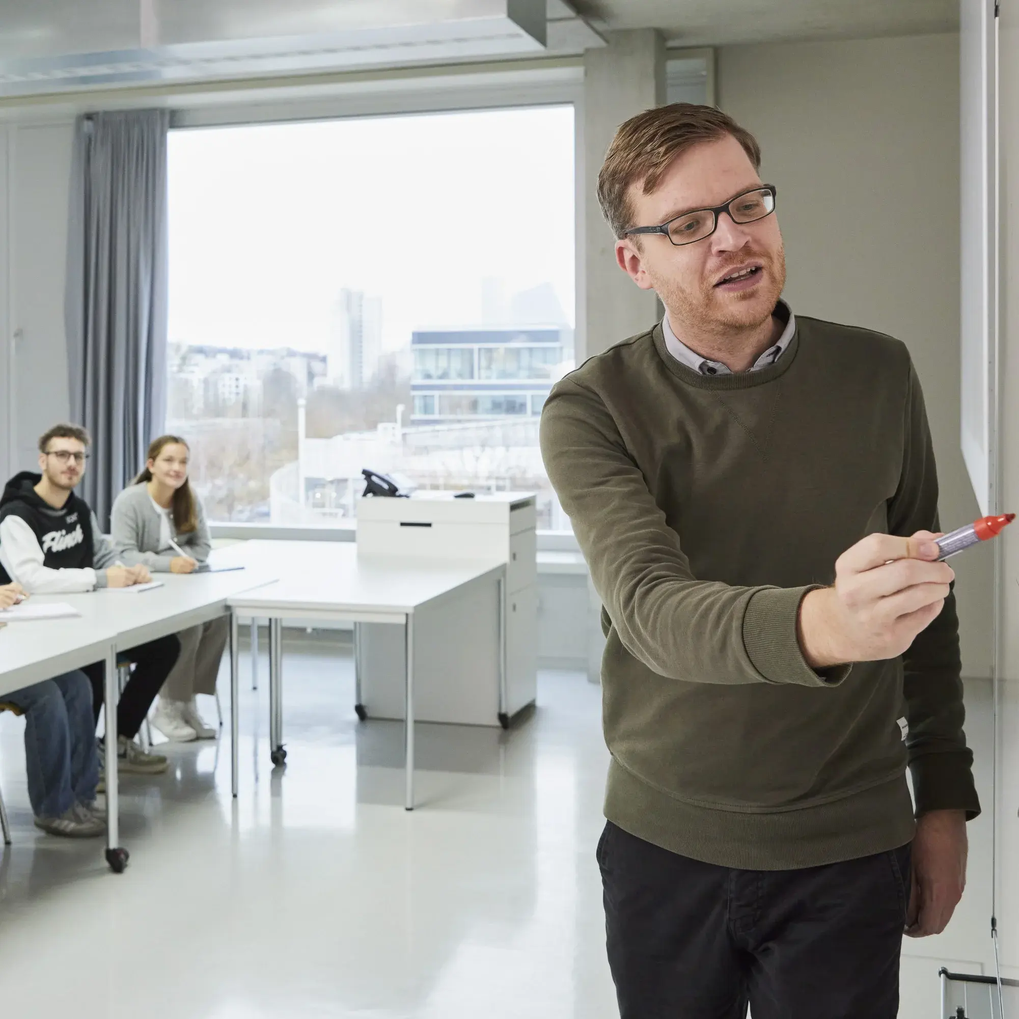 Ein Professor malt in seiner Vorlesung etwas auf die Tafel.