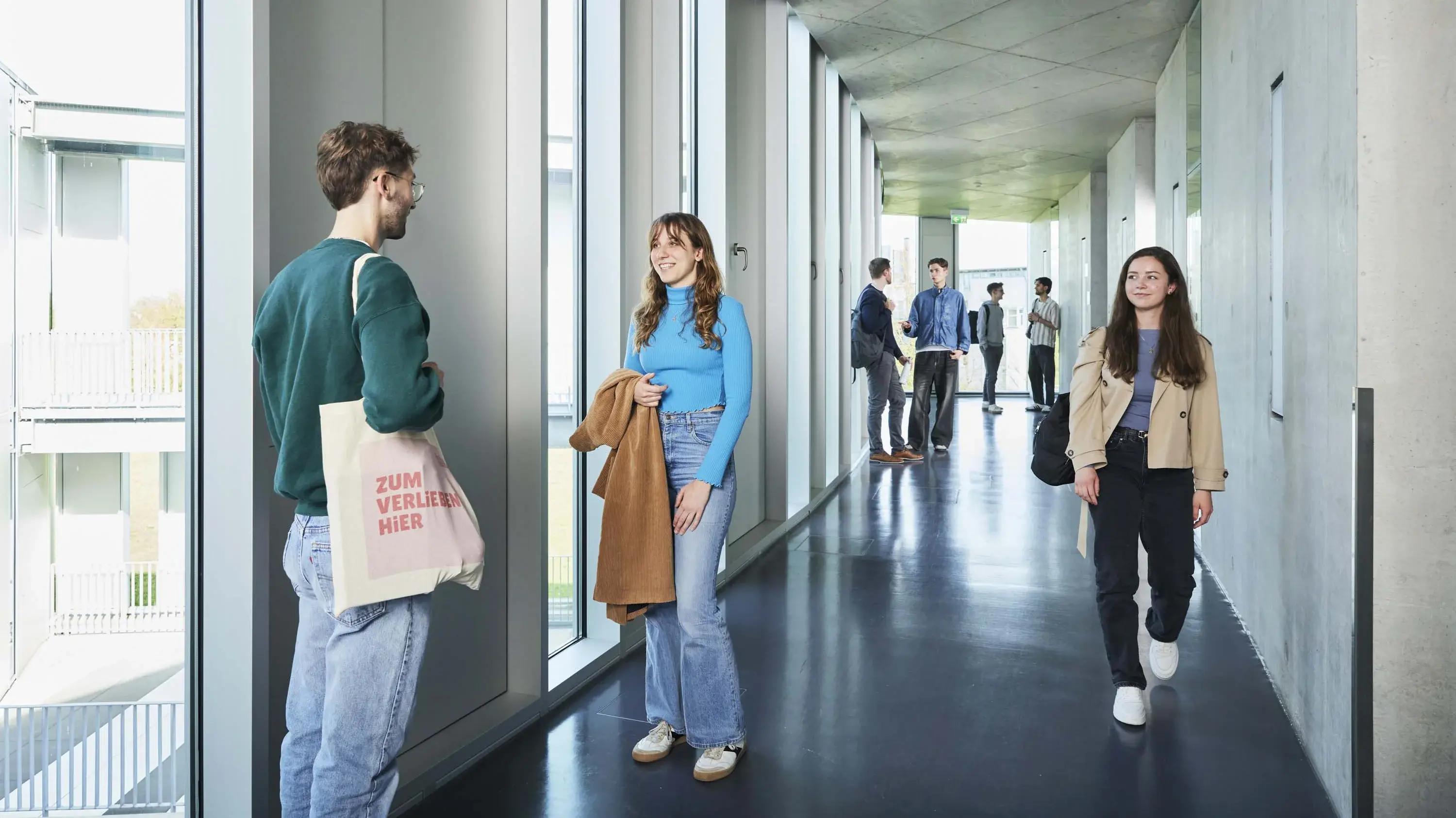 Studierende unterhalten sich in den Gängen auf dem Campus.