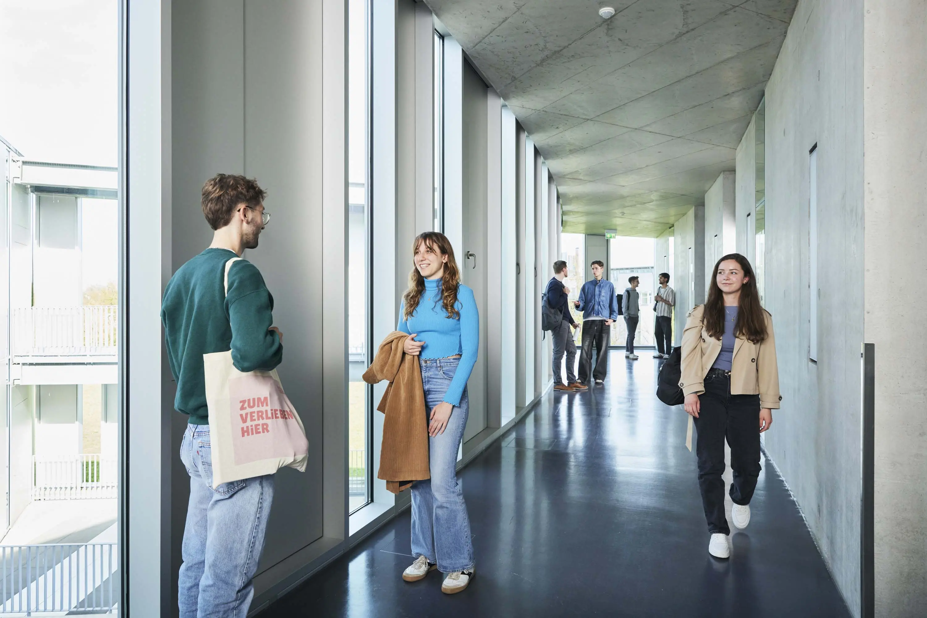 Studierende unterhalten sich in den Gängen auf dem Campus.