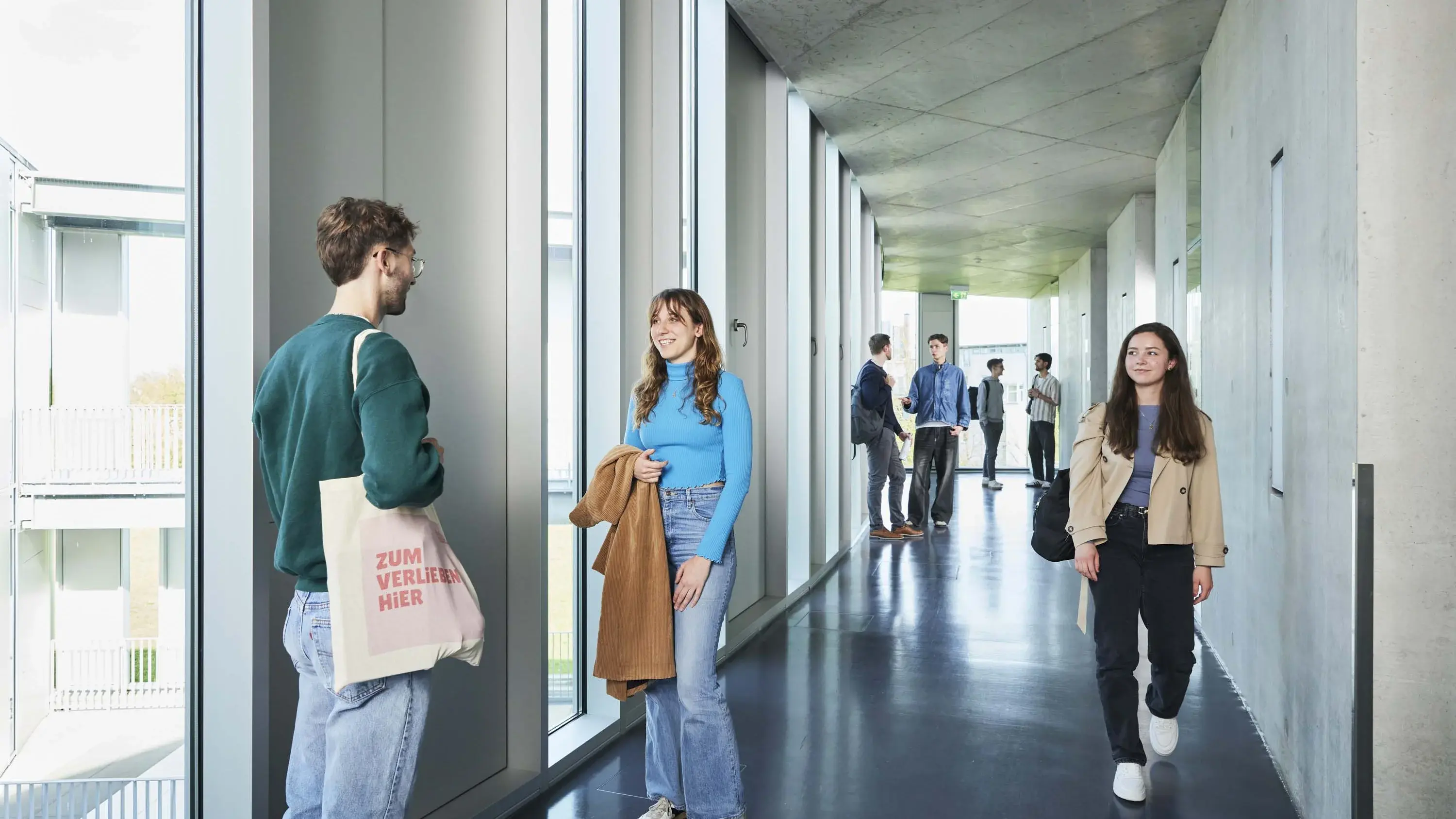 Studierende unterhalten sich in den Gängen auf dem Campus.