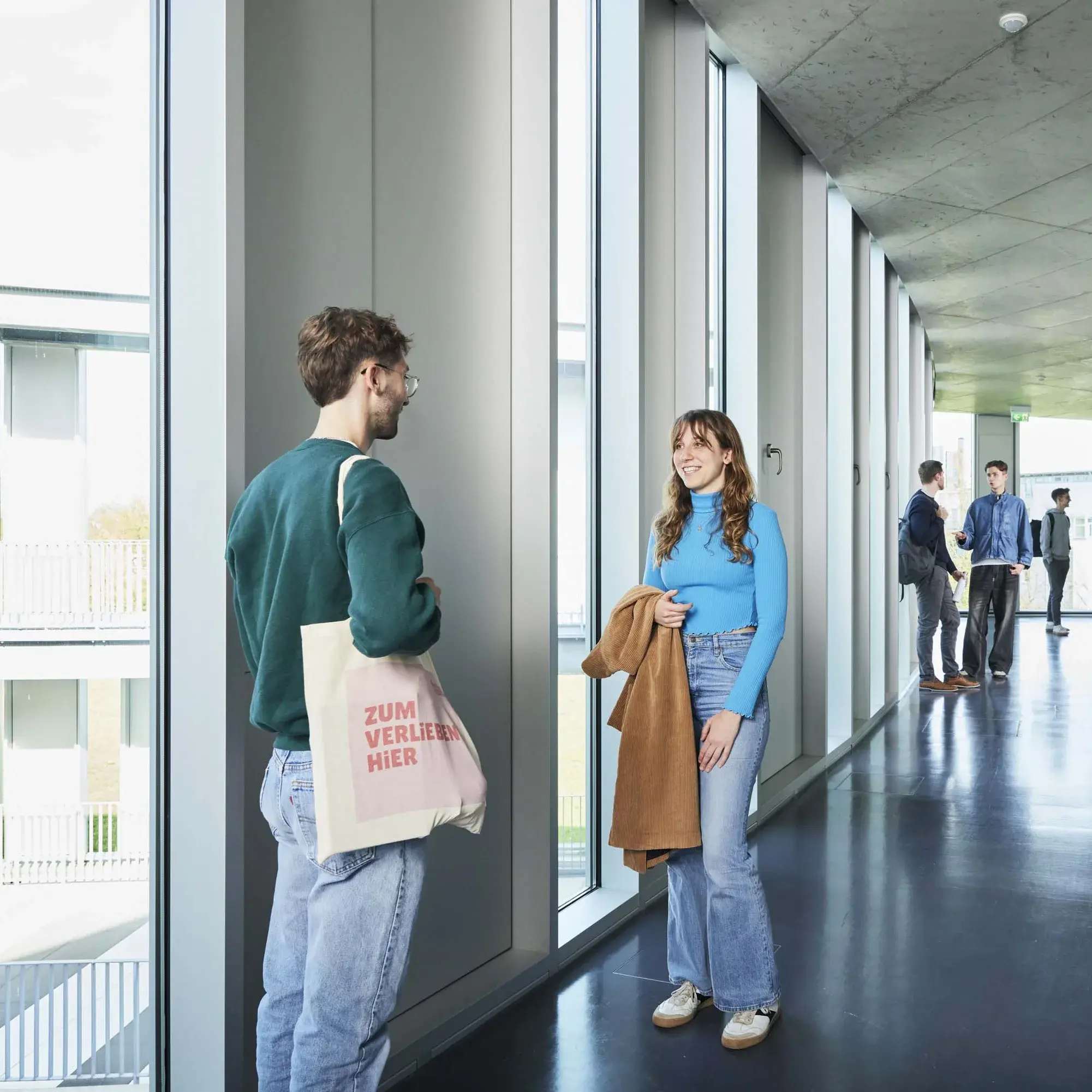 Studierende unterhalten sich in den Gängen auf dem Campus.