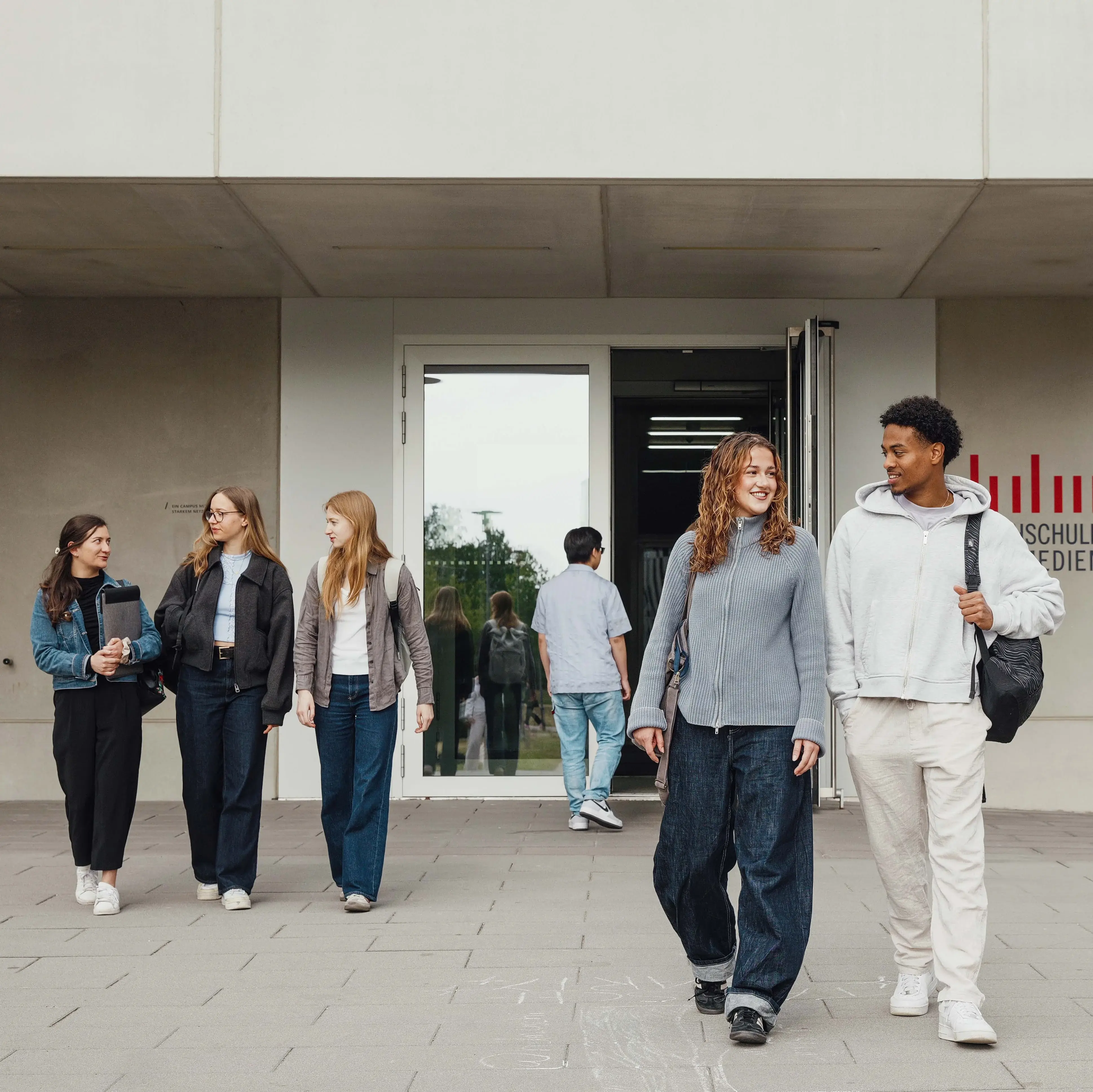 Studierende unterhalten sich beim Verlassen der Hochschule der Medien.