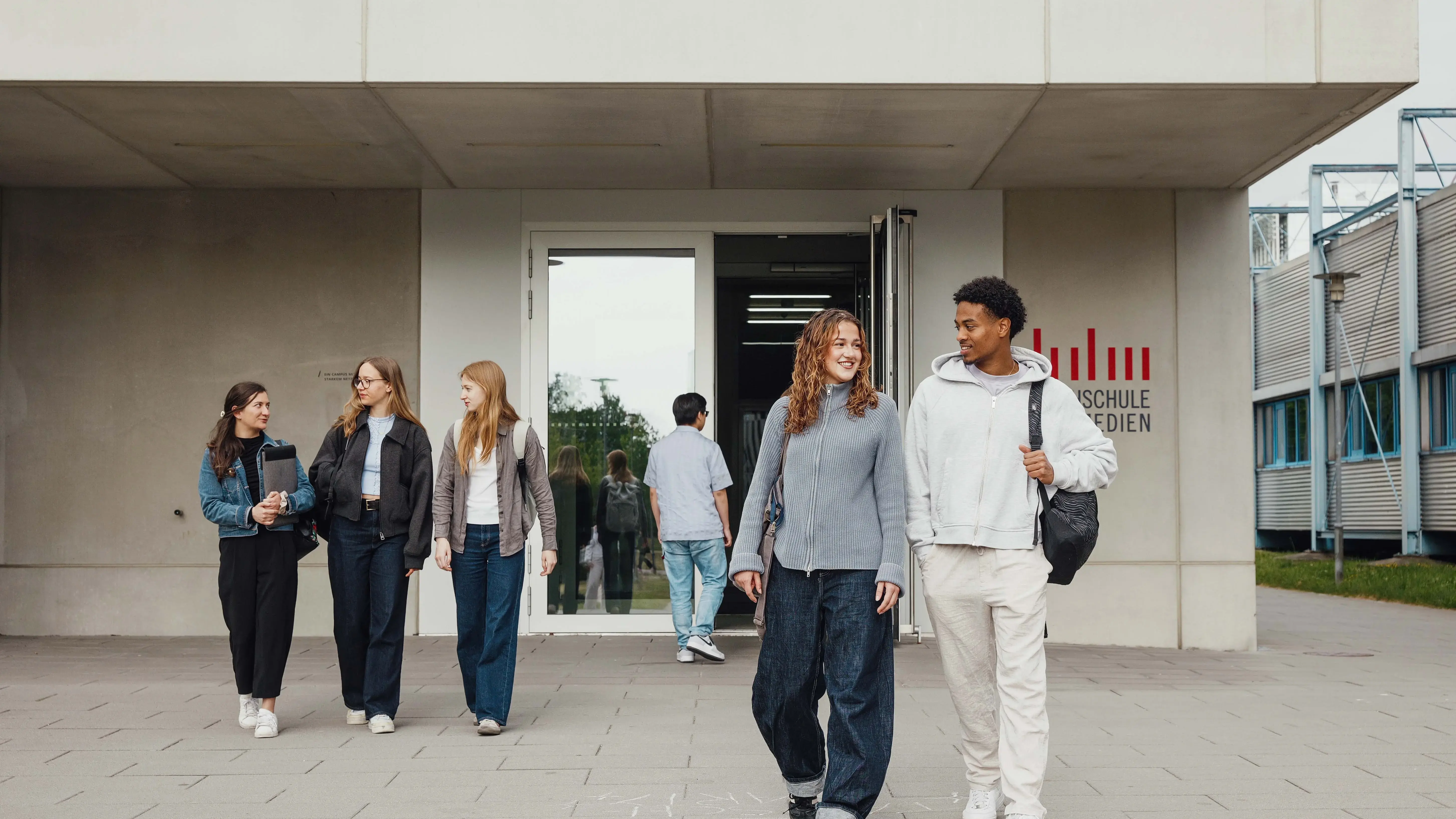 Studierende unterhalten sich beim Verlassen der Hochschule der Medien.
