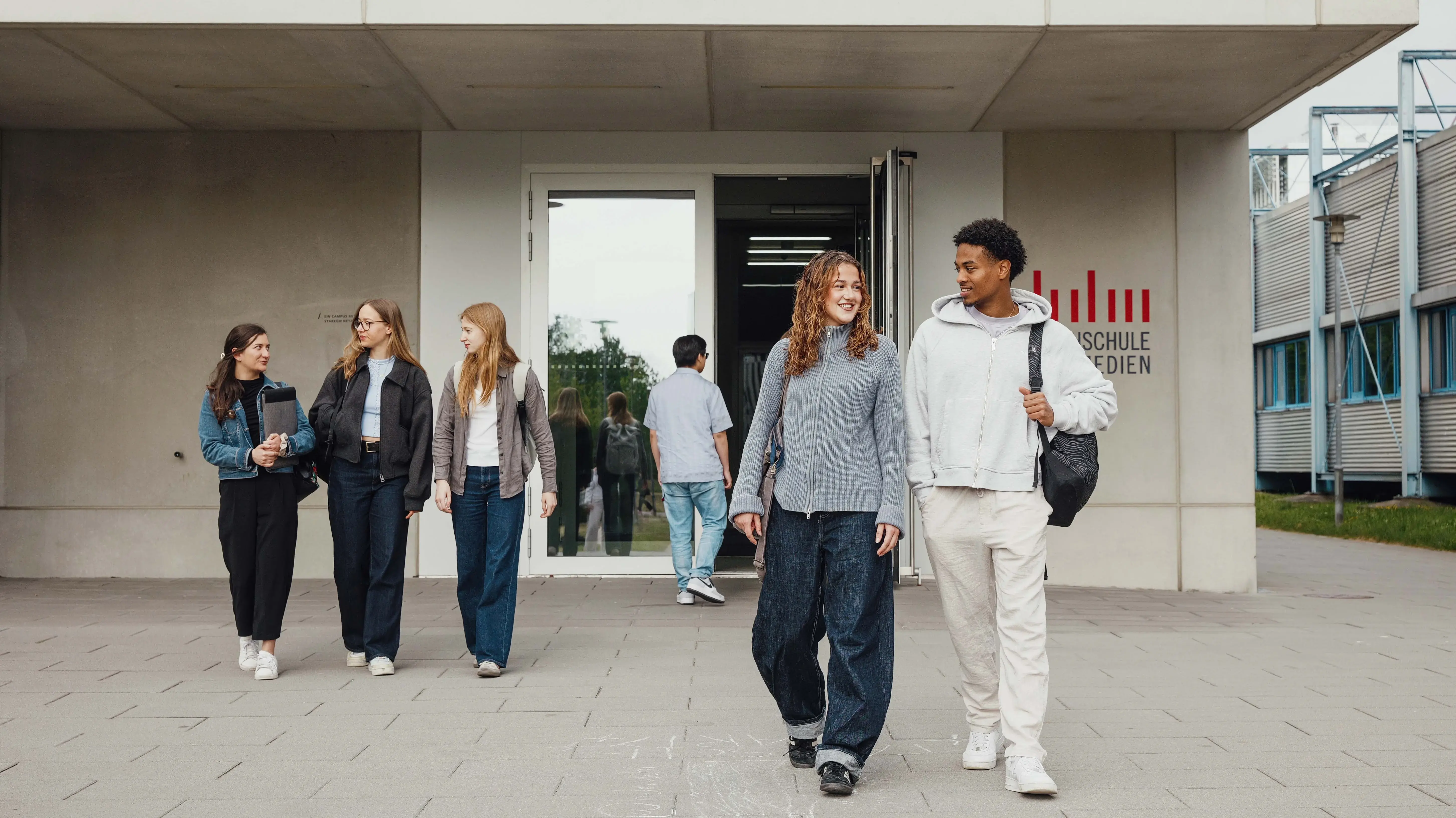 Studierende unterhalten sich beim Verlassen der Hochschule der Medien.