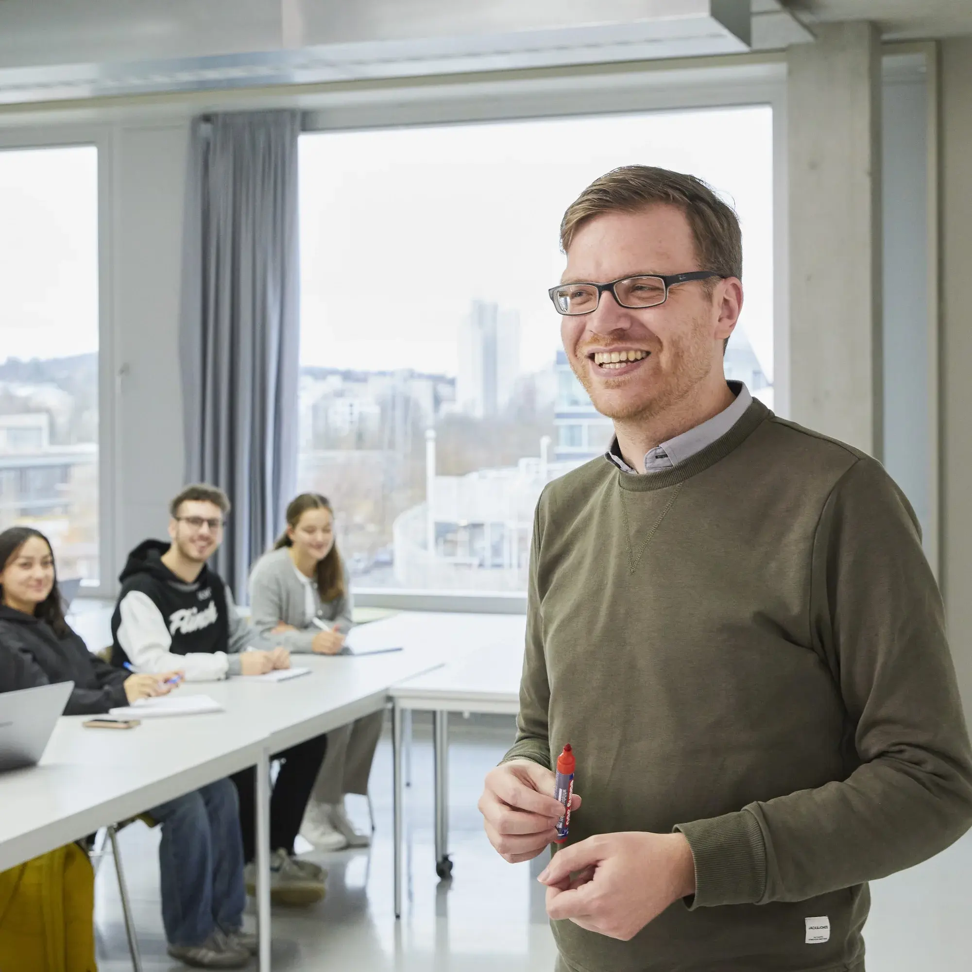 Professor lächelt während einer Vorlesung in die Kamera.