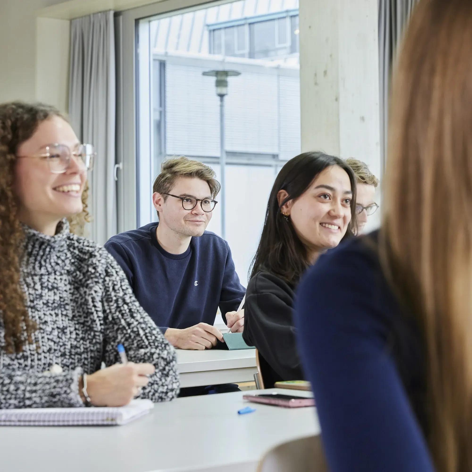 Studierende sitzen lachend in einer Vorlesung.