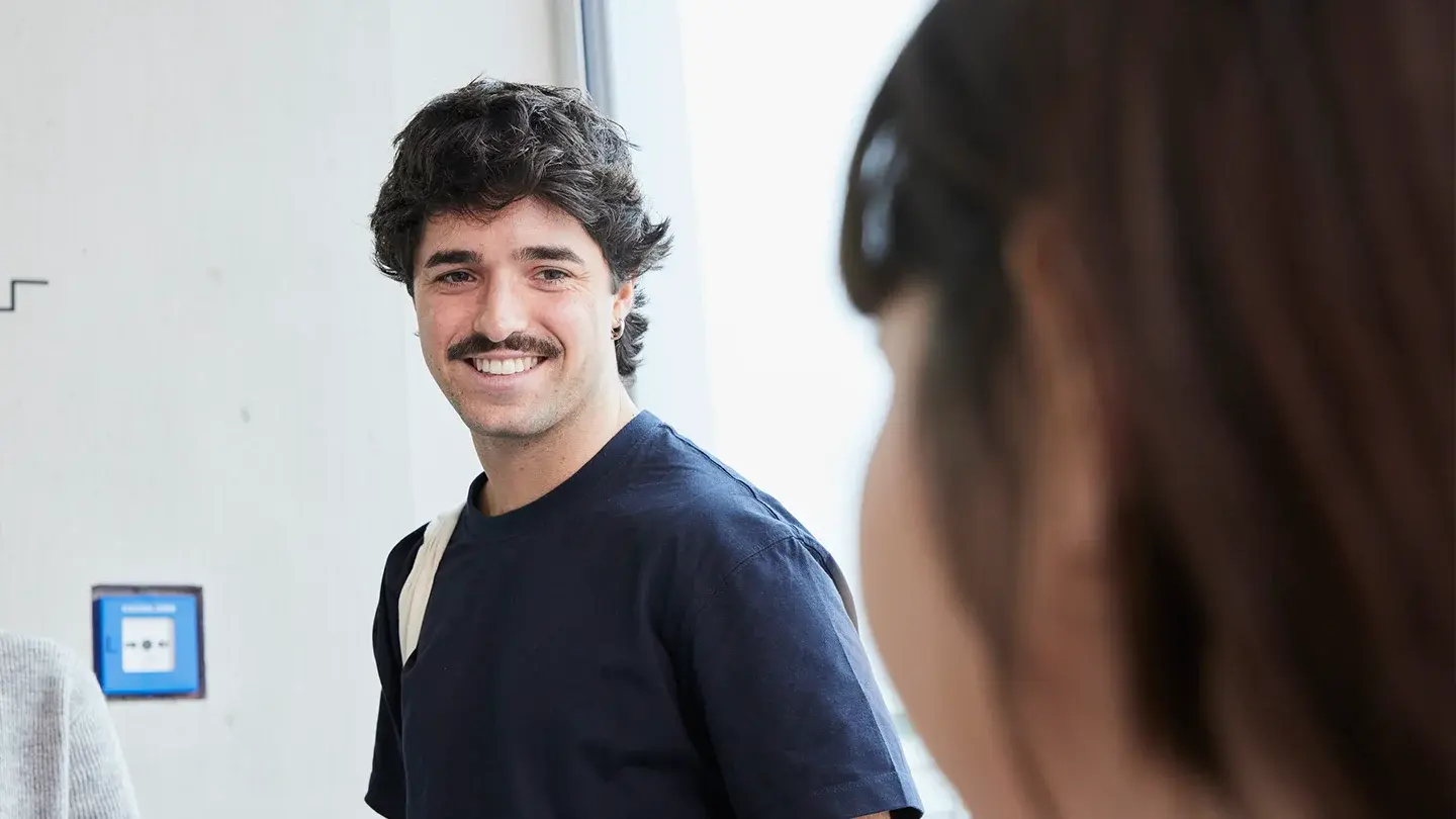 Ein Studierender lächelt eine andere Studierende an.